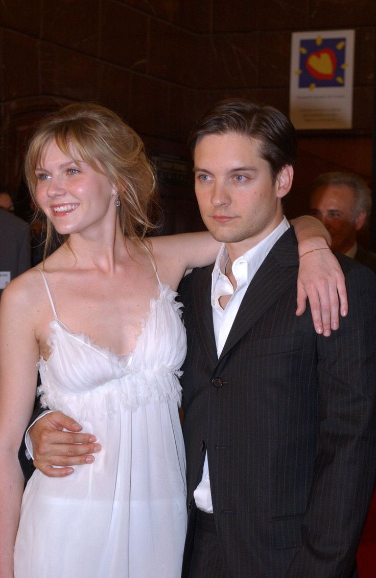 a man and woman standing next to each other in front of a red carpeted room