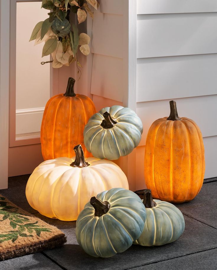 four pumpkins sitting on the ground in front of a house