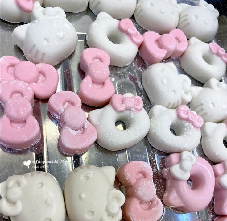 hello kitty donuts with pink and white frosting are on a baking sheet, ready to be baked