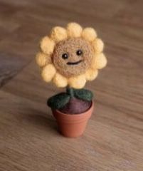 a small toy sunflower sitting on top of a potted plant with a smiley face