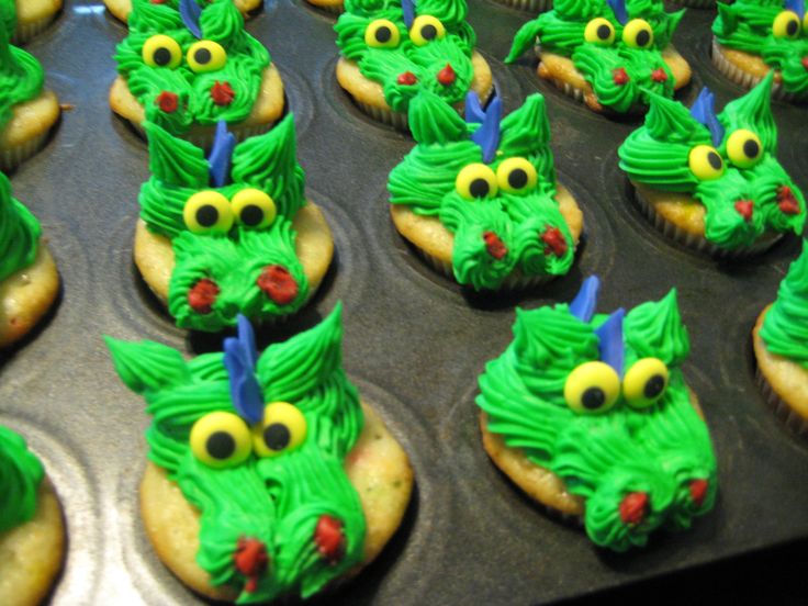 cupcakes decorated with green frosting and googly eyes are sitting in a muffin tin