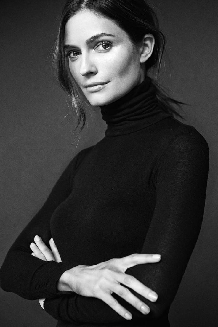 a black and white photo of a woman wearing a turtle neck sweater with her arms crossed