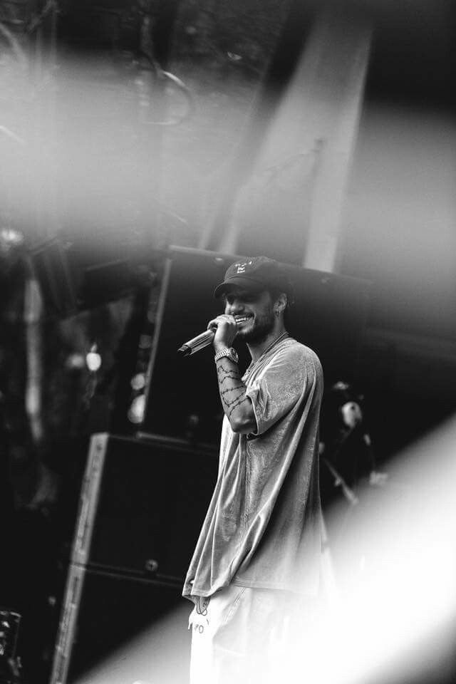 a black and white photo of a man holding a microphone to his ear while standing in front of a stage