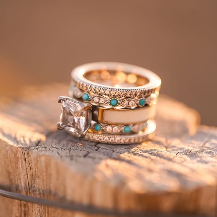 two wedding rings sitting on top of a piece of wood with turquoise stones in them