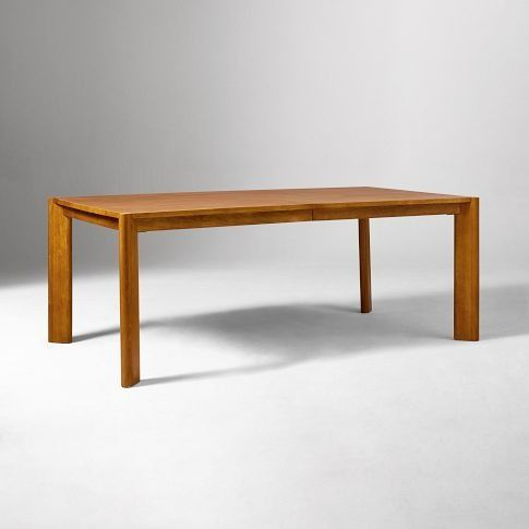 a wooden table sitting on top of a white floor next to a gray wall in an empty room