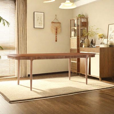 a living room with hardwood floors and white walls, along with a large wooden table in the center