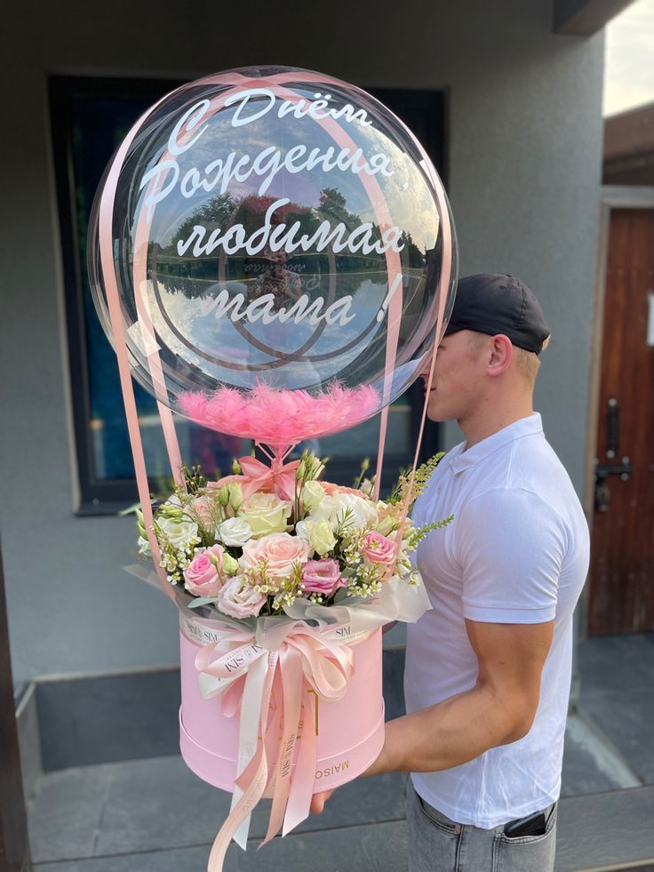 a man is holding a large balloon with flowers in it