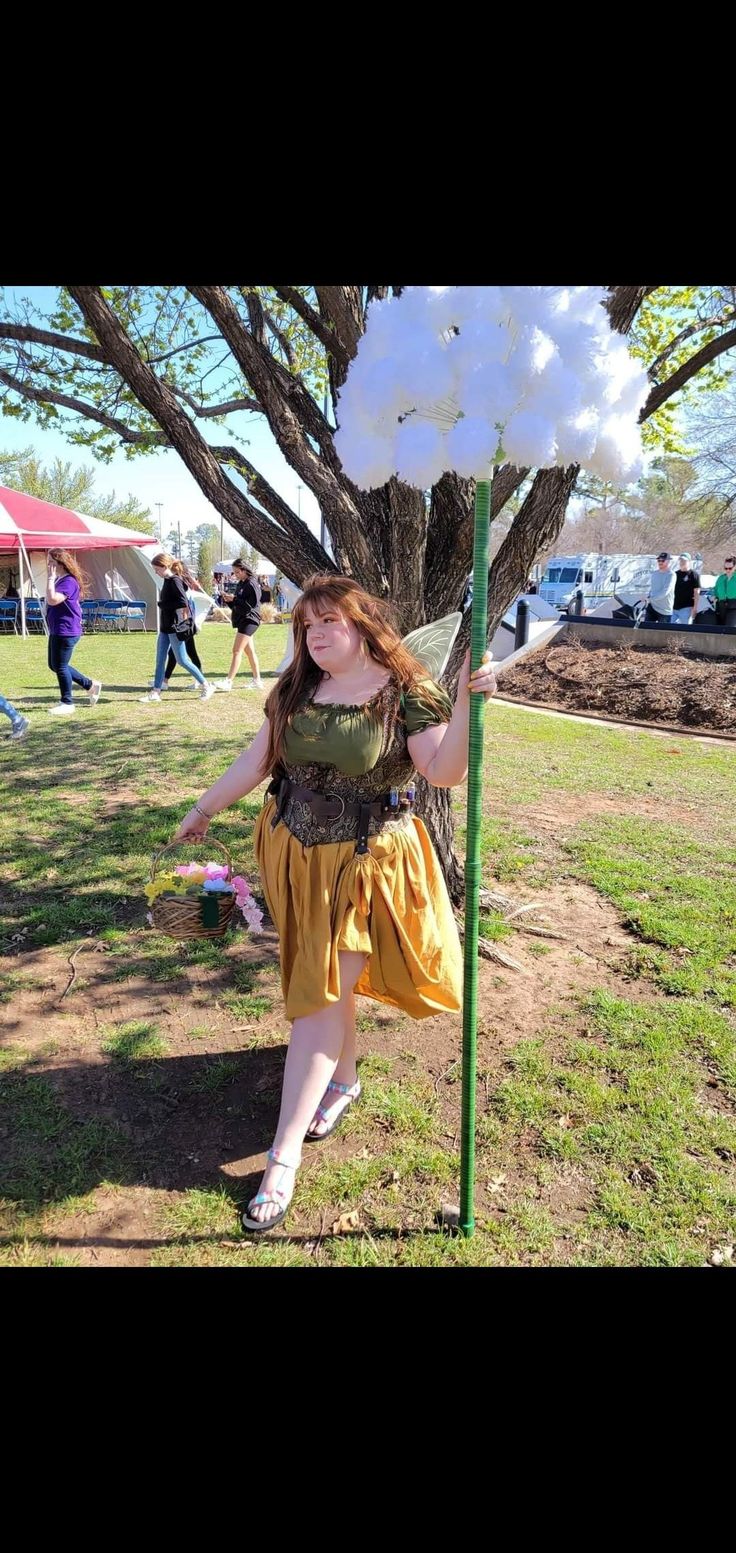 a woman dressed as tinkerbell standing next to a pole with cotton candy on it