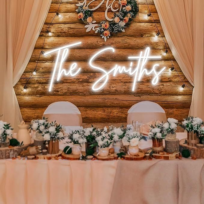 the wedding reception table is set up with white flowers and greenery, along with an illuminated sign that says the swittes