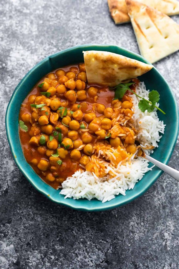 a bowl filled with rice and chickpeas next to pita bread on the side