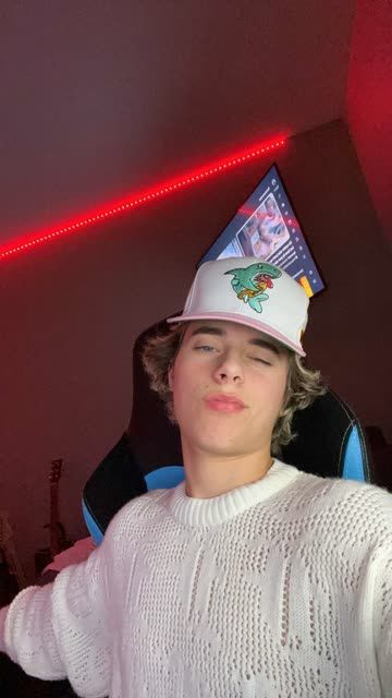 a young man wearing a birthday hat in a room with red light coming from the ceiling