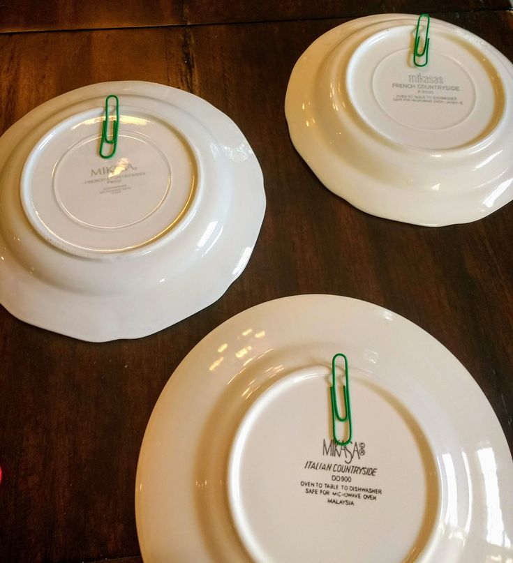 three white plates sitting on top of a wooden table next to each other with green tags