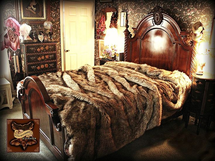 a bed with fur on it in a bedroom next to a dresser and table lamp