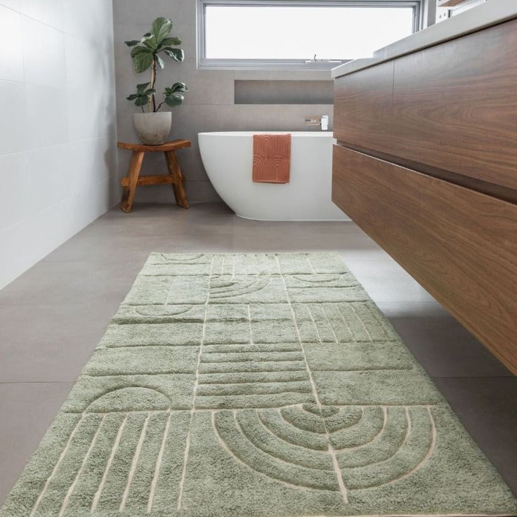 a bathroom with a bathtub, toilet and rug on the floor in front of it