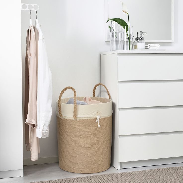 a white closet with a large round basket and clothes hanging on the wall next to it