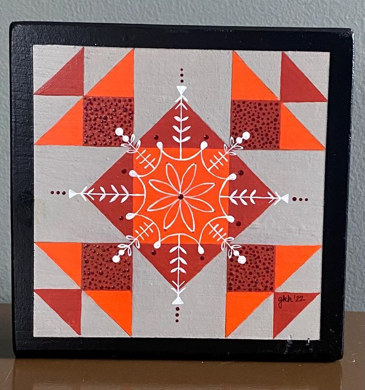 an orange and white patchwork design on a black frame