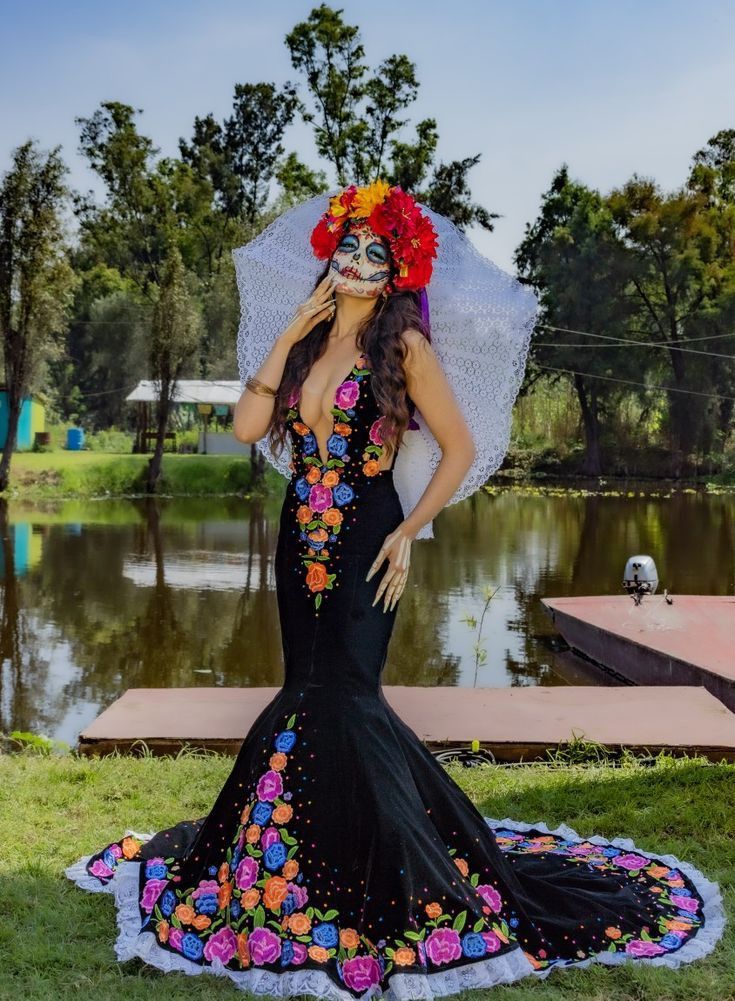 a woman in a black dress with flowers on her head and an umbrella over her head