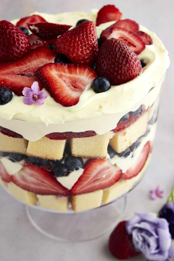 a layered cake with strawberries and blueberries on top