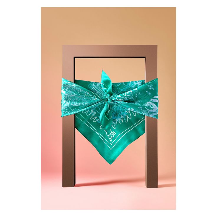 a green bandana tied to a wooden frame on a pink background with the word love written across it