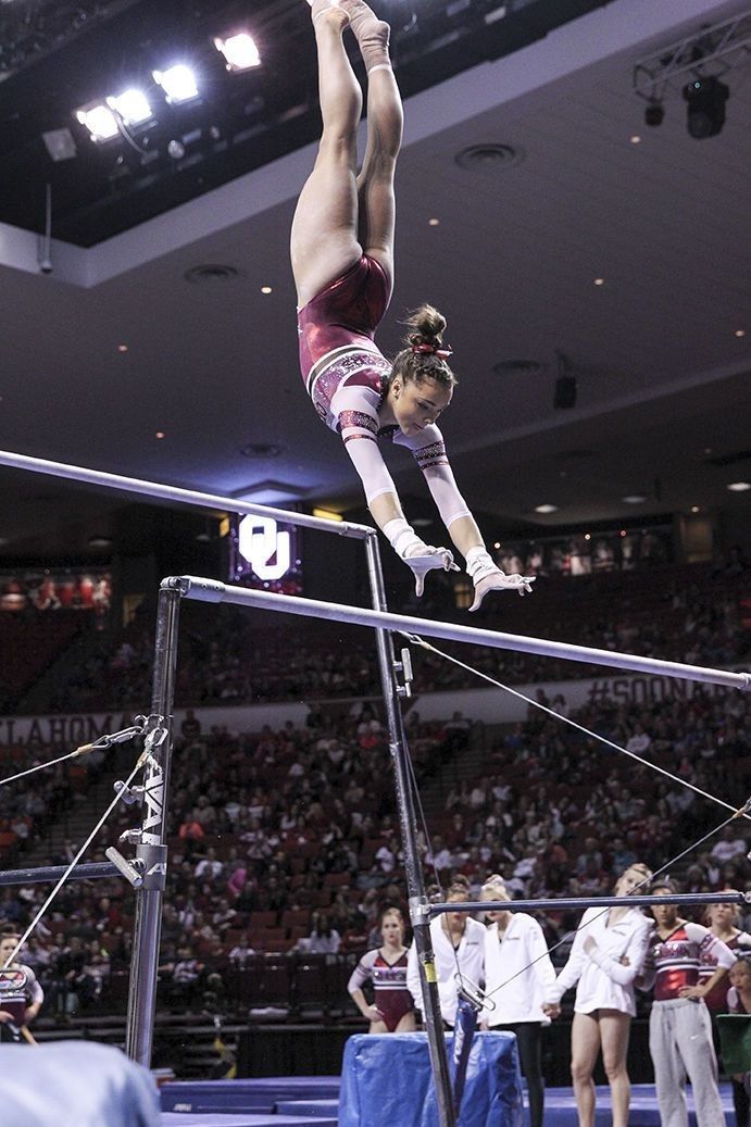 a woman is performing on the balance bars in front of an arena full of people