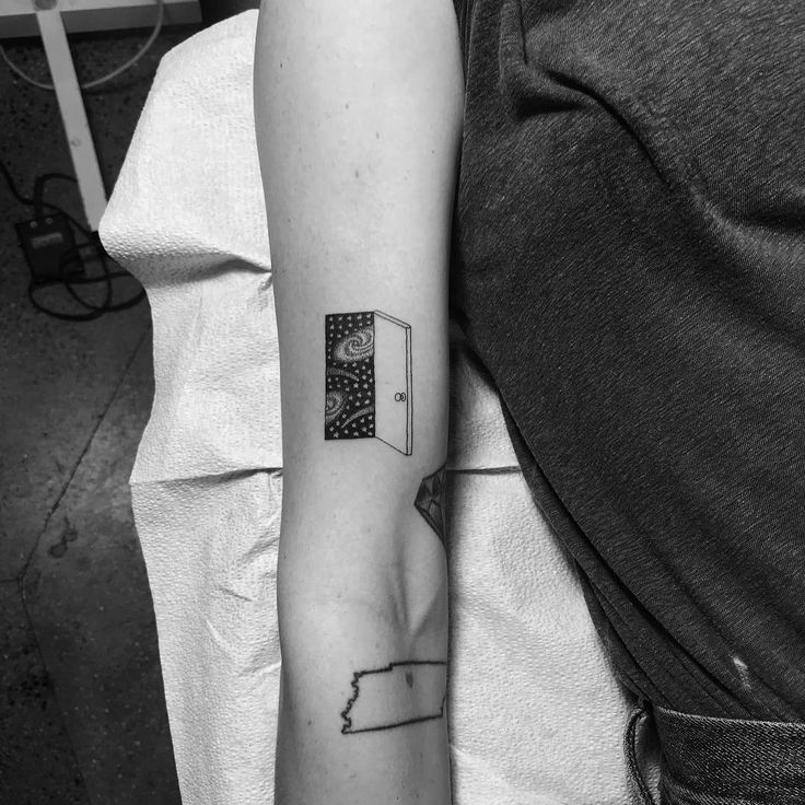 a black and white photo of a person's arm with a book on it