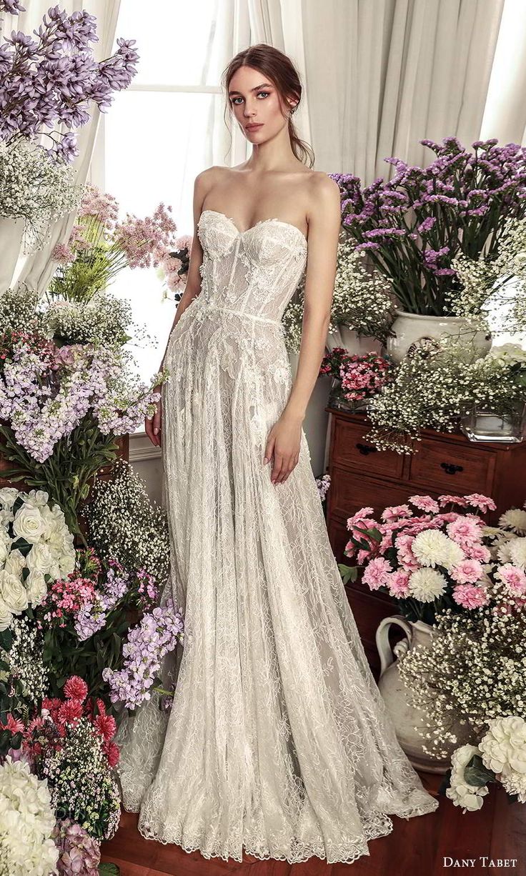 a woman standing in front of flowers wearing a wedding dress