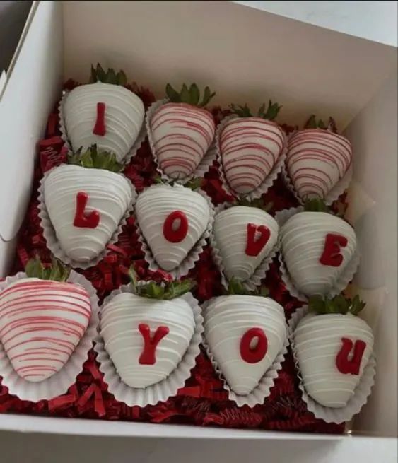 chocolate covered strawberries in a box with i love you written on them