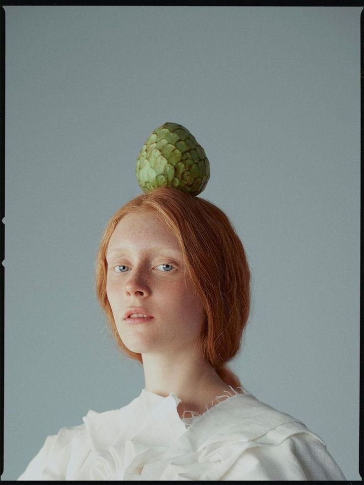 a woman with red hair wearing a white dress and a green headpiece