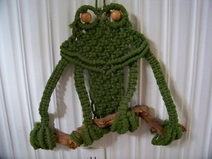 a crocheted frog is hanging on the wall