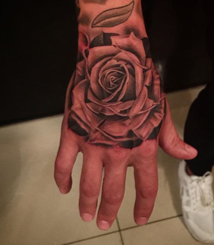 a man's hand with a rose tattoo on it