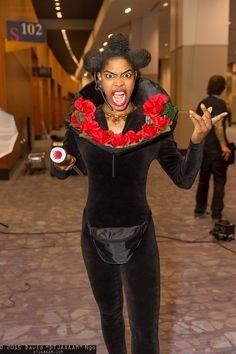 a woman dressed in black and red with flowers on her head posing for the camera