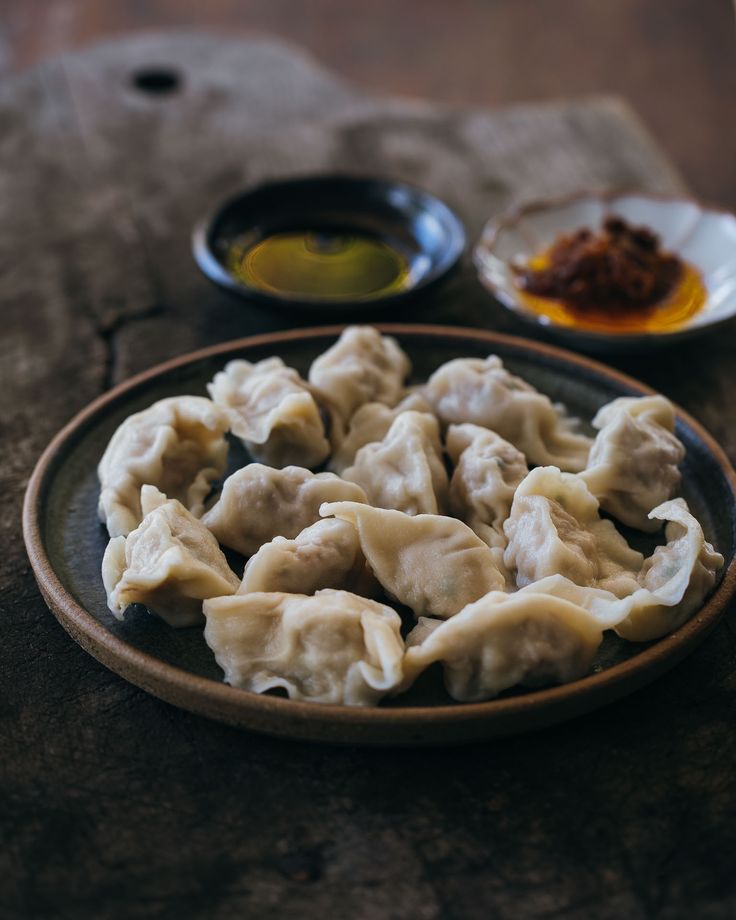 some dumplings are sitting on a plate with dipping sauce