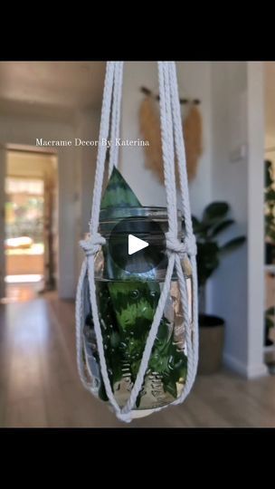 a glass jar filled with plants hanging from a rope