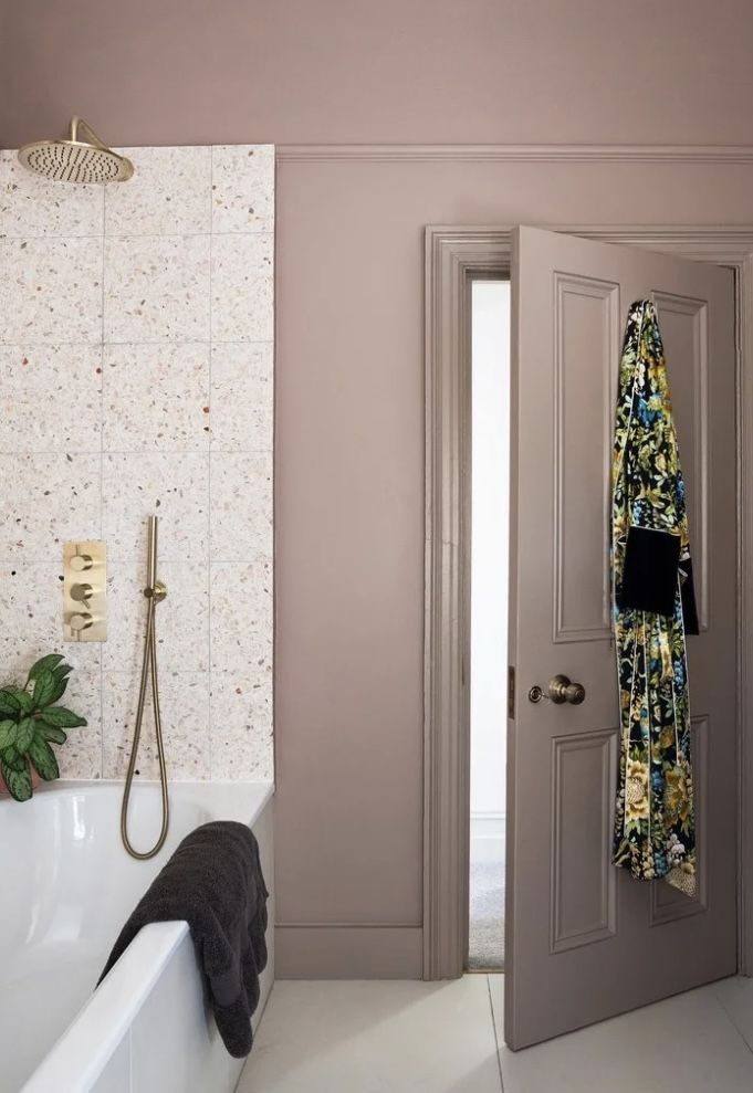 a bath room with a tub a shower and a plant on the wall next to it