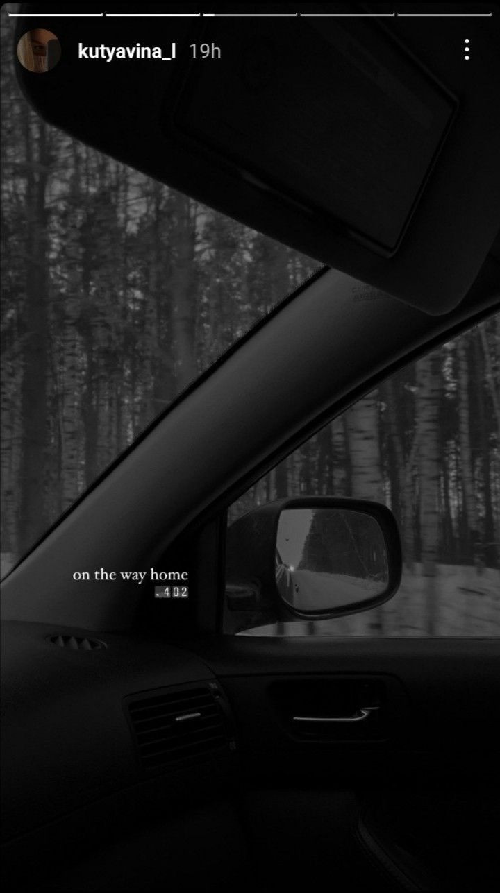 the rear view mirror of a car is shown in black and white, with trees behind it