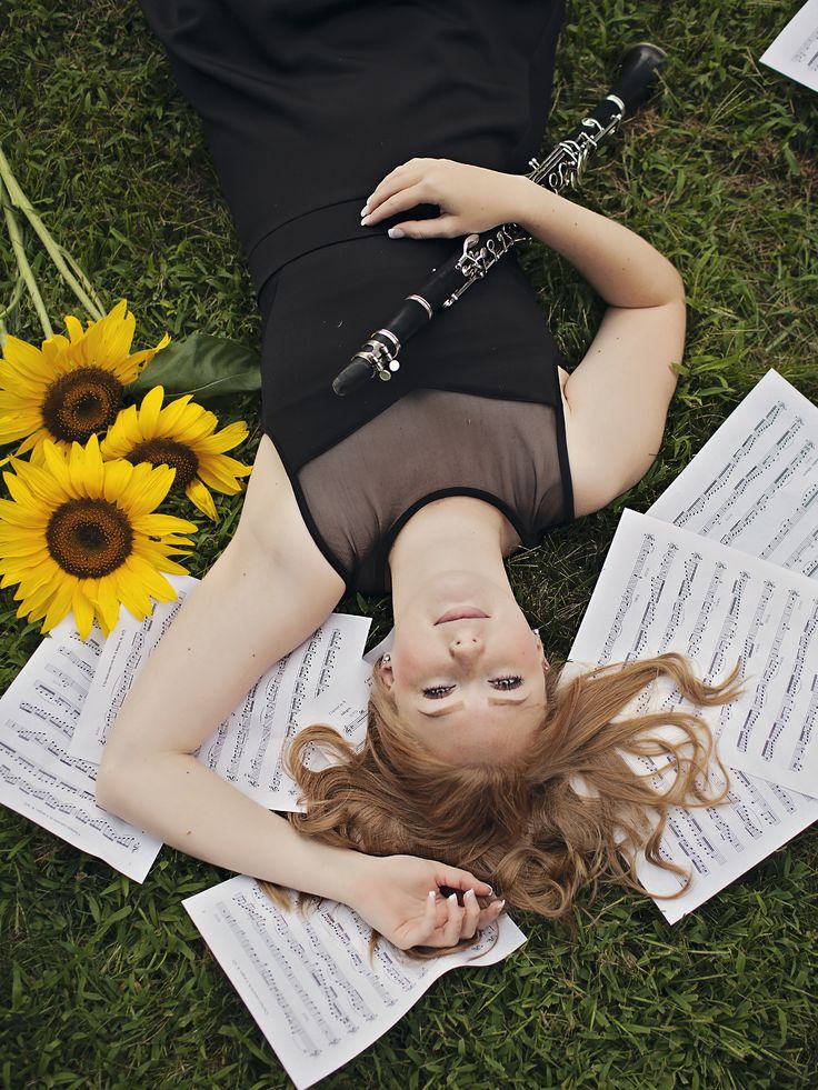 a woman laying on the ground with music sheets and sunflowers in front of her