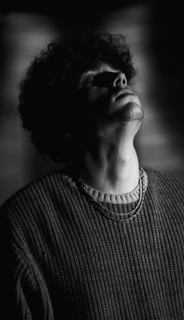 a black and white photo of a man with his eyes closed looking up to the sky