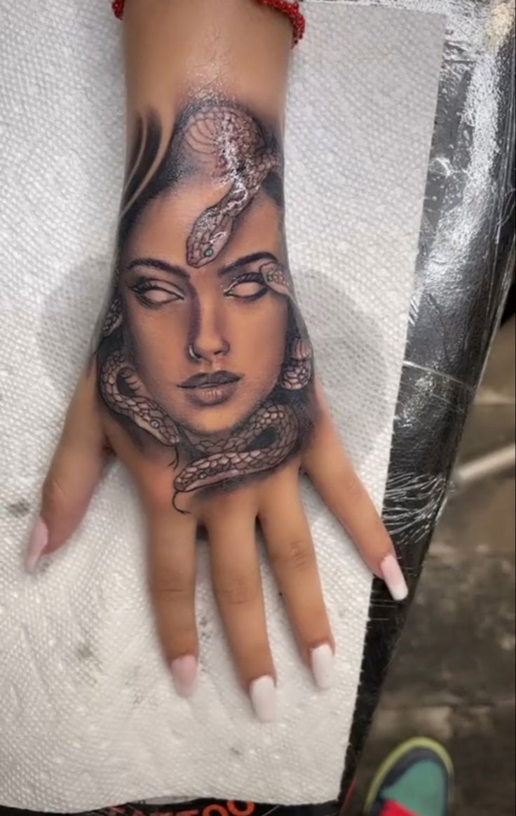 a woman's hand with a tattoo on it and a snake around her wrist