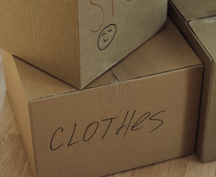 two boxes with clothes written on them sitting on a wooden floor next to each other