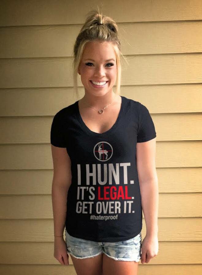 a woman standing in front of a house wearing a shirt that says i hunt it's legal get over it