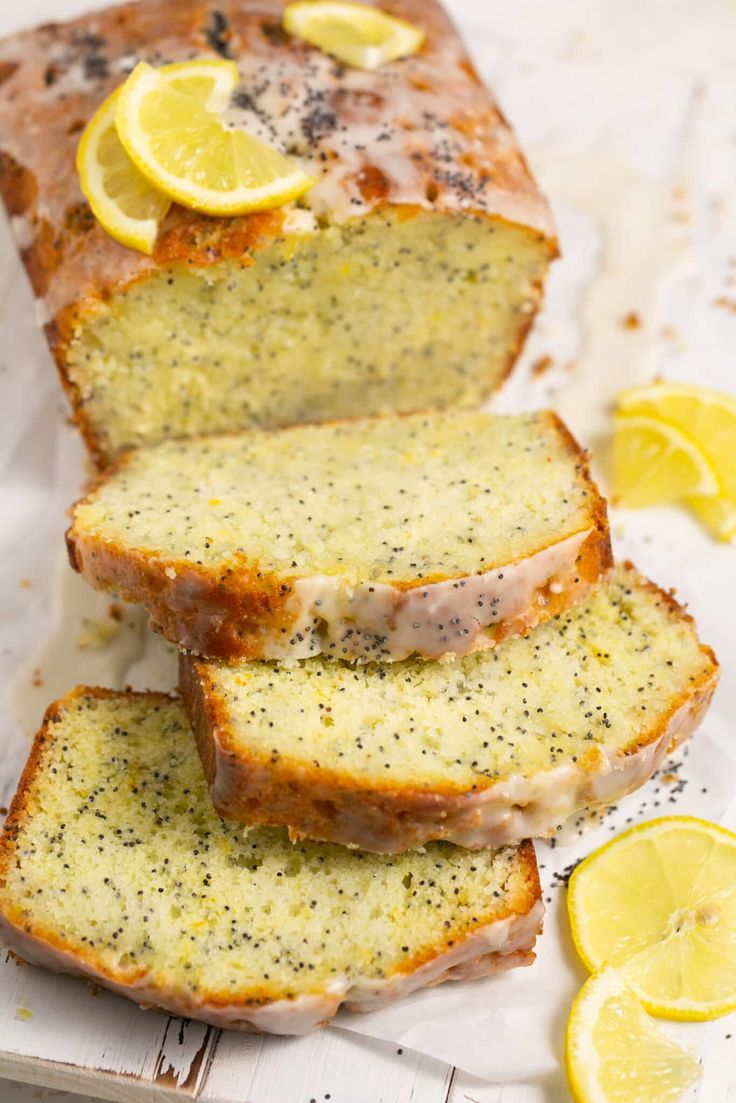 slices of lemon poppy seed bread on top of white parchment paper with sliced lemons