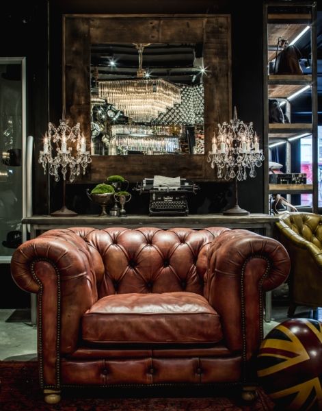 a brown leather chair sitting in front of a bar with chandelier hanging from the ceiling