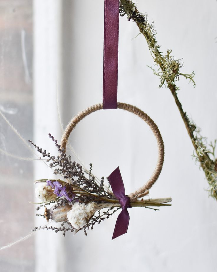 a wreath hanging from the ceiling with purple ribbon and dried flowers in front of it