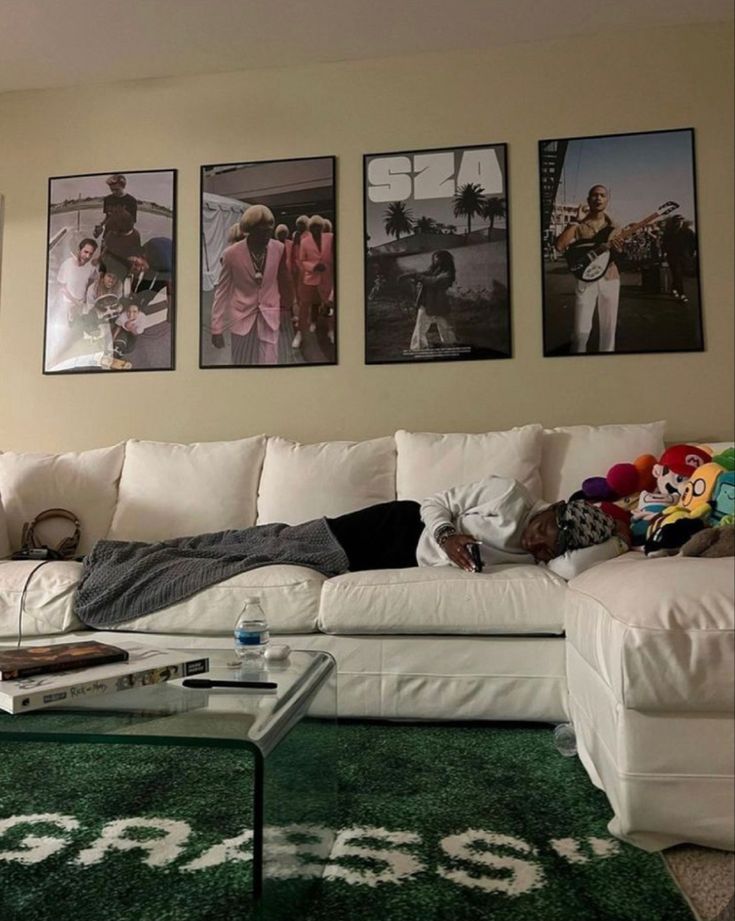 a living room filled with white furniture and pictures on the wall above it's coffee table