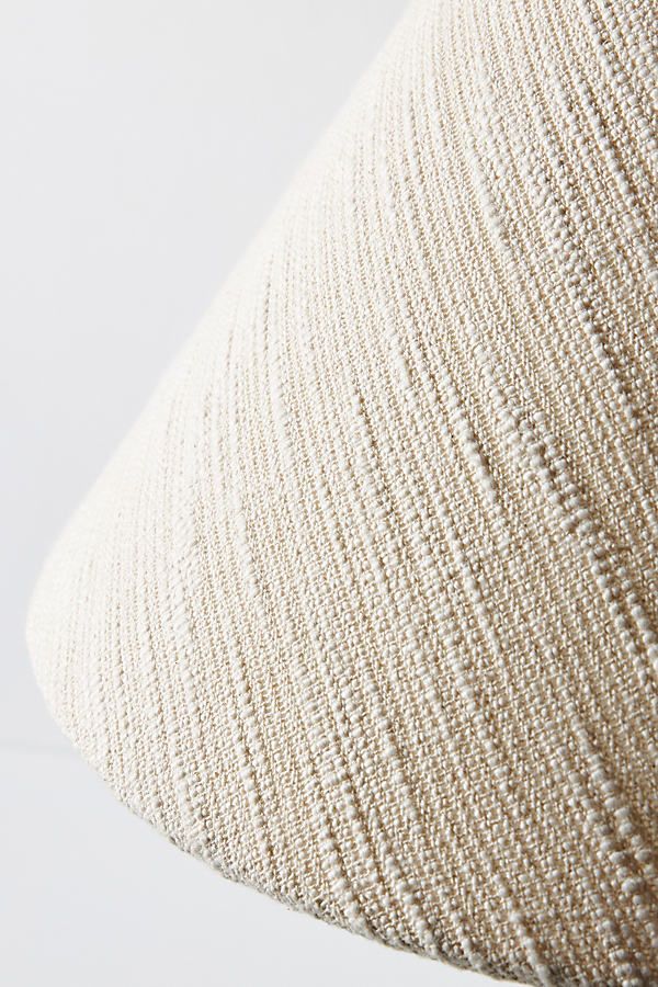 a close up view of a beige pillow on a white surface with the fabric pulled back