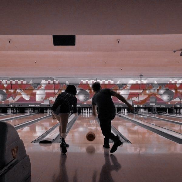 two people are bowling in a bowling alley