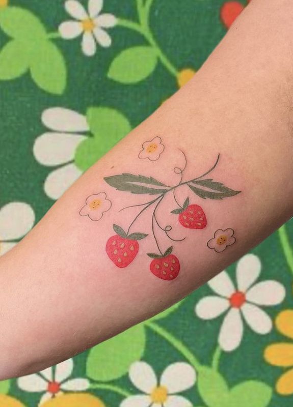 a woman's arm with flowers and strawberries on the left side of her arm