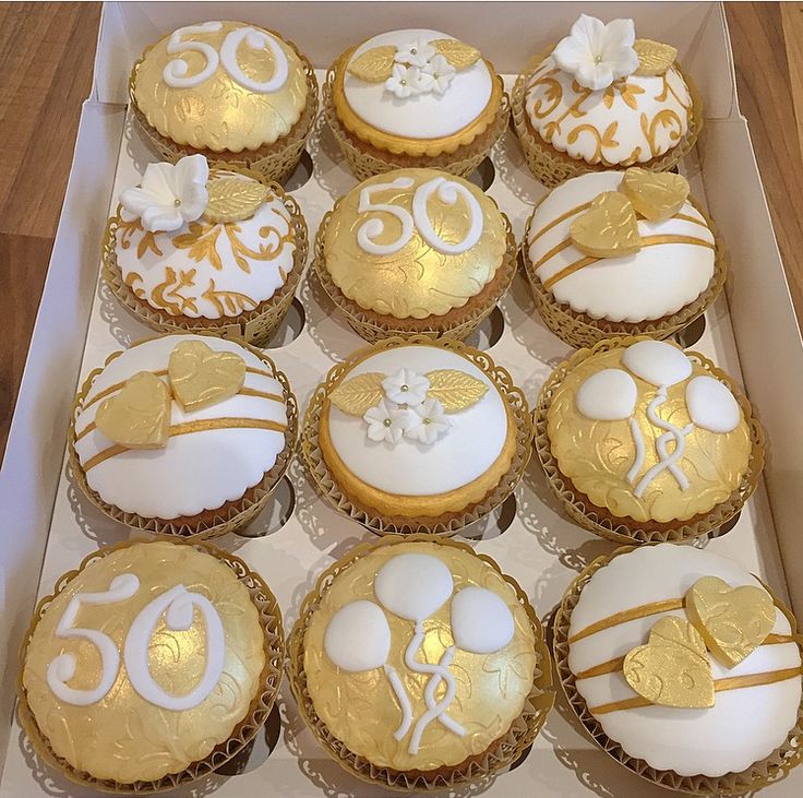 a box filled with lots of cupcakes covered in white and gold frosting