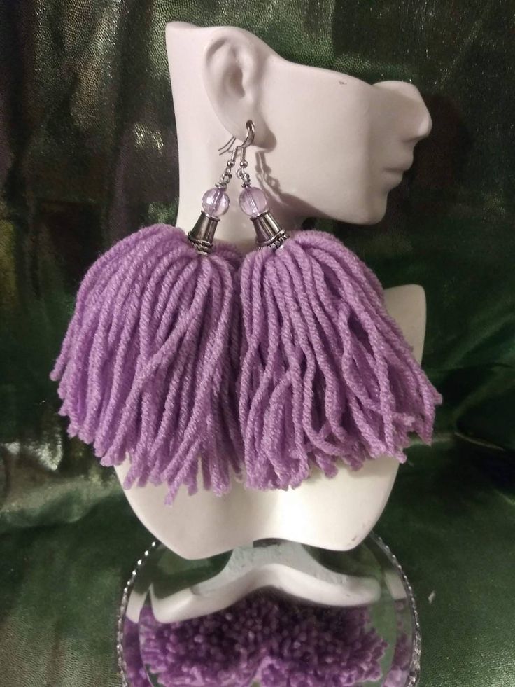 a white mannequin head with purple earrings on it