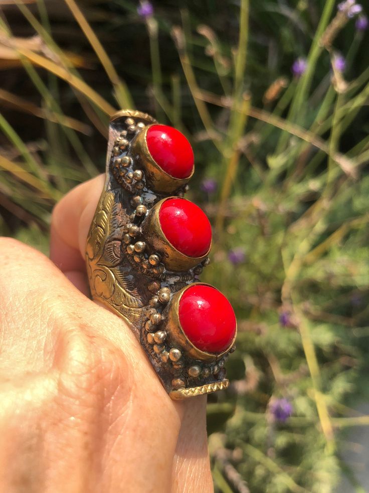 Beautiful vintage tribal saddle full finger ring Red gemstones or glass? Brass intricate carving Adjustable between sizes 9- 11. This is a gorgeous and very unique finger ring. There are three round cut cabochons and I am not sure what they are made of, they could be gemstone or they could be glass. The ring itself appears to be brass and someone could probably give it a good polishing if desired although I think it adds to the character the way it is. The ring Can fit anywhere from a size 9 thr Bohemian Toe Ring Jewelry For Ceremonial Occasions, Bohemian Toe Ring Jewelry For Ceremonies, Unique Red Stone Jewelry, Vintage Festival Ring, One Of A Kind Red Jewelry For Festivals, Unique One Of A Kind Jewelry For Festivals, Unique Ceremonial Toe Ring, Unique Carved Ring Jewelry, Unique Red Jewelry For Ceremonial Occasion